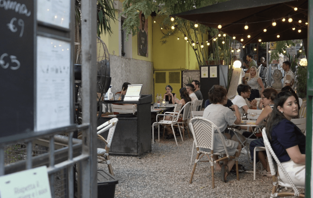 People eat at tables on a garden patio.