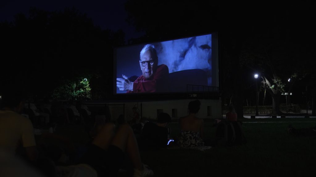 A movie playing on an outdoor movie screen.