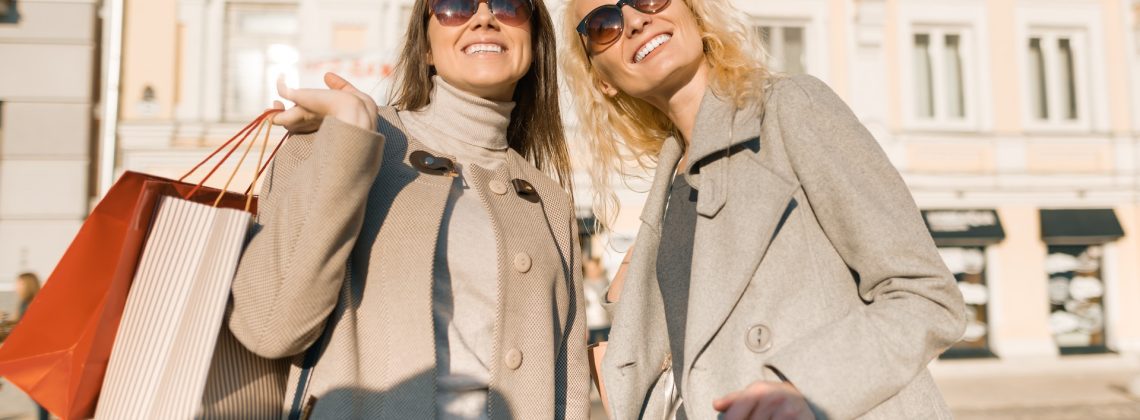Women smiling while holding shopping bags.
