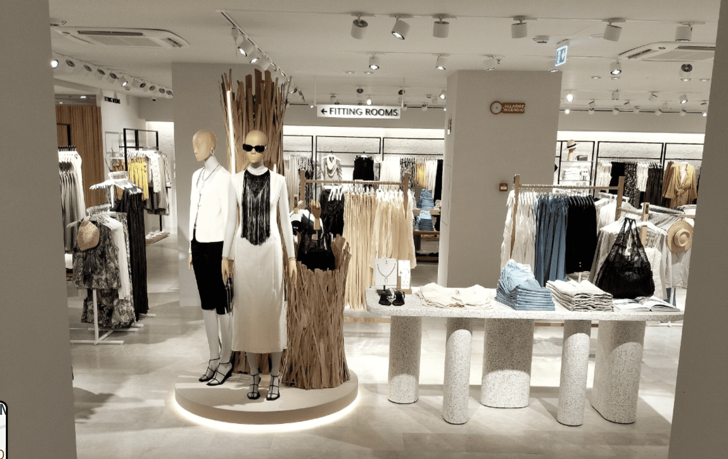 White store space with folded jeans and sweaters on tables.