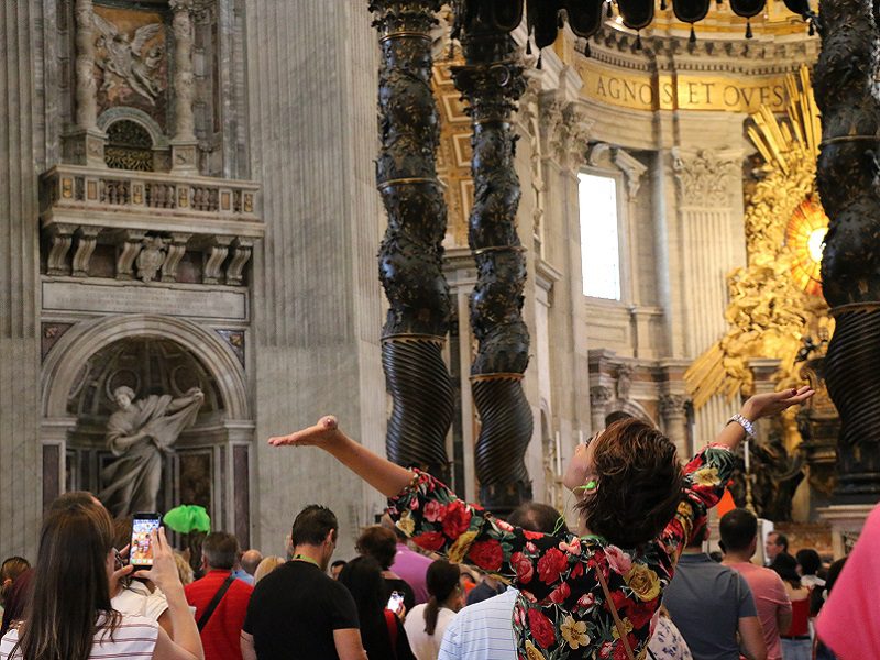 Woman standing in Vatican with arms outstretched.