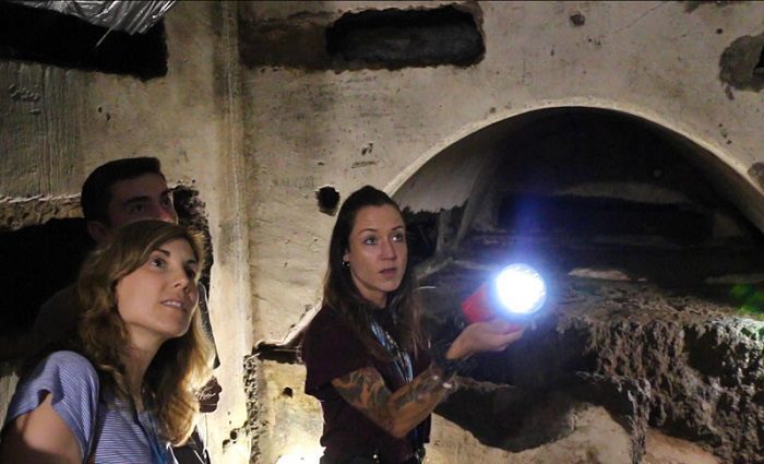 Visitors and a guide in the Rome Catacombs at night on an after hours guided tour