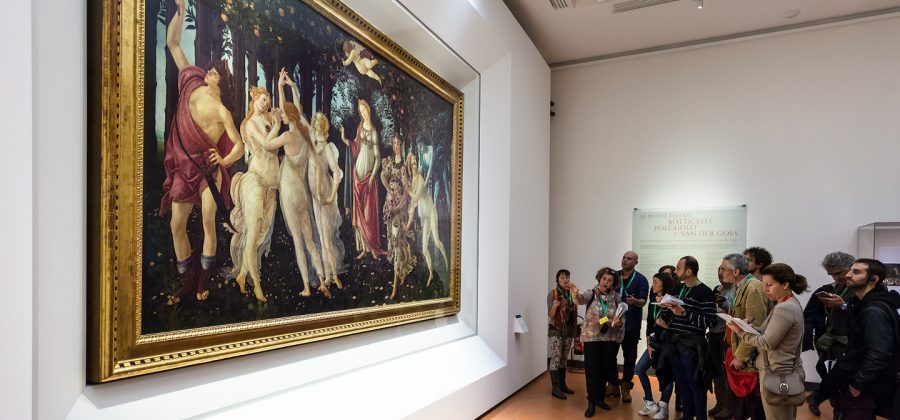 visitors in Botticelli hall of Uffizi Gallery admiring La Primavera painting.