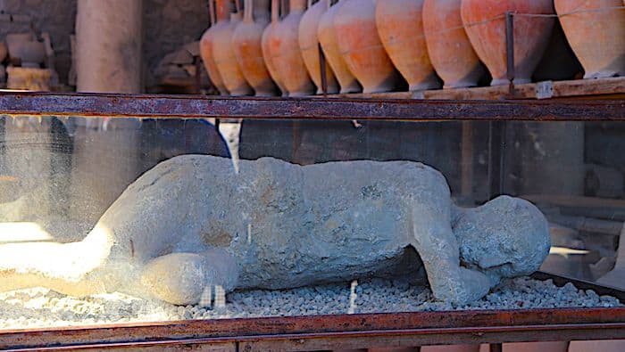 The preserved plaster cast of a victim laid on their side during the volcanic eruption that destroyed Pompeii.