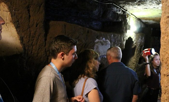 a small group of people on a private tour in the Rome catacombs. 