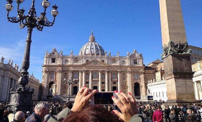 Exterior view of St. Peter's Basilica in Rome with crowds of people out front.